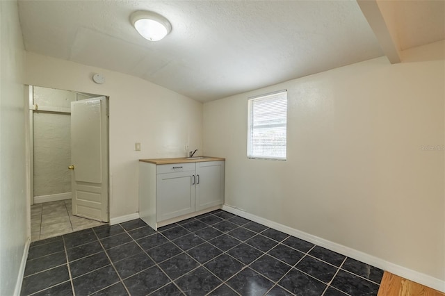 clothes washing area with sink and dark tile patterned floors