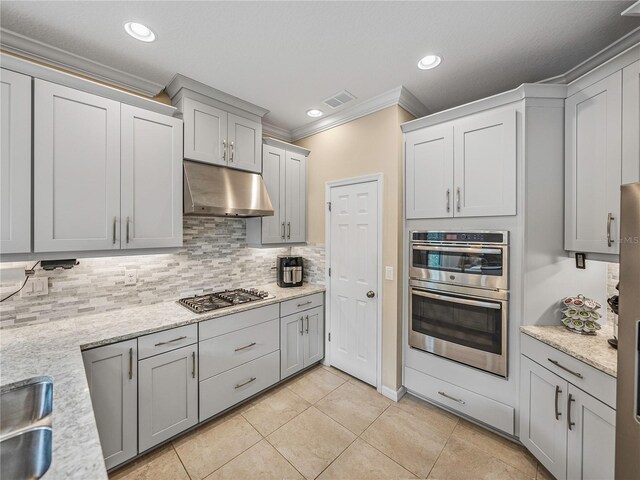 kitchen with stainless steel appliances, light stone counters, decorative backsplash, light tile patterned flooring, and ornamental molding