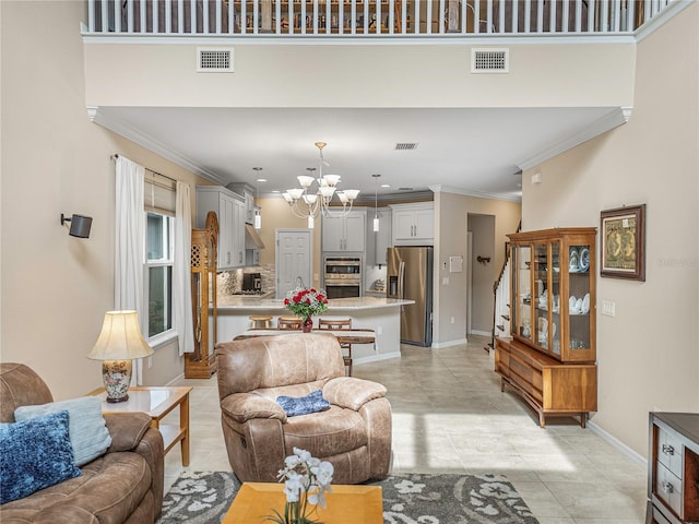 living room featuring light tile patterned floors, a high ceiling, ornamental molding, and a notable chandelier