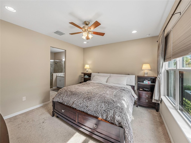 bedroom with ceiling fan, light colored carpet, and connected bathroom