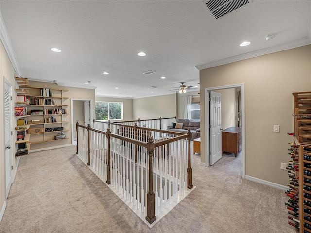 corridor featuring a textured ceiling, light colored carpet, and crown molding