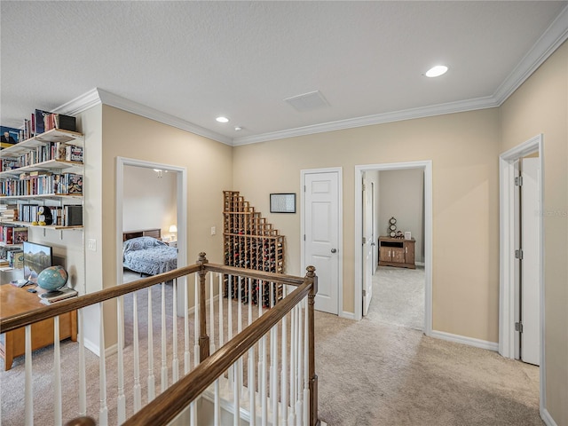 hall featuring a textured ceiling, ornamental molding, and light carpet