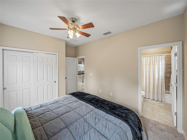 bedroom featuring ceiling fan, light tile patterned flooring, ensuite bath, and a closet