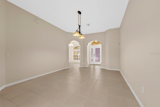 tiled empty room featuring french doors and a chandelier