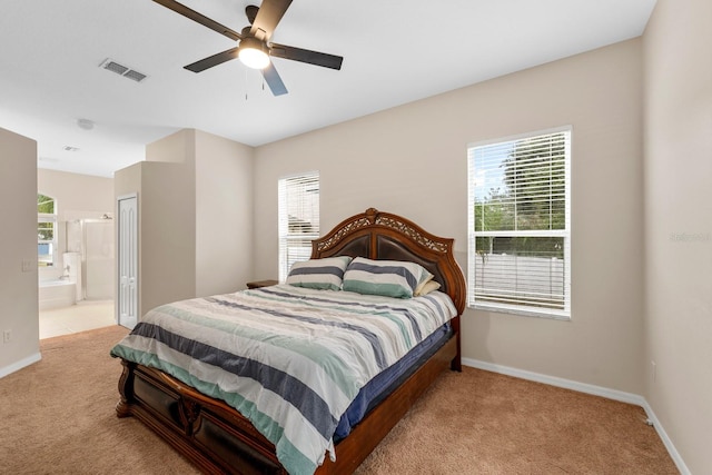 carpeted bedroom with ceiling fan, connected bathroom, and multiple windows