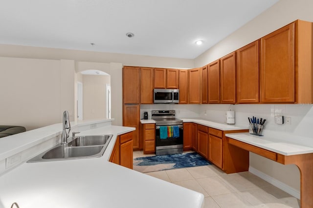 kitchen with sink, kitchen peninsula, decorative backsplash, light tile patterned floors, and appliances with stainless steel finishes