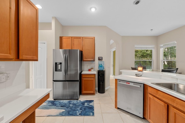 kitchen featuring backsplash, sink, light tile patterned floors, and stainless steel appliances