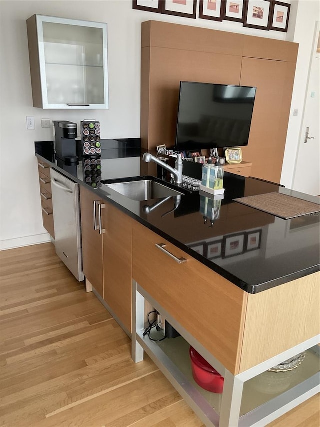 kitchen with stainless steel dishwasher, sink, and light hardwood / wood-style flooring