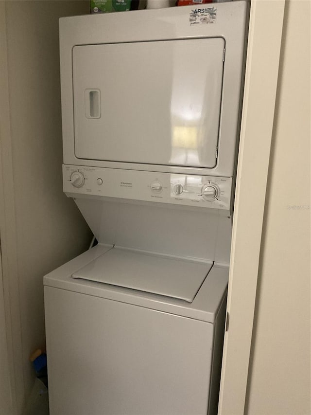 clothes washing area with stacked washing maching and dryer