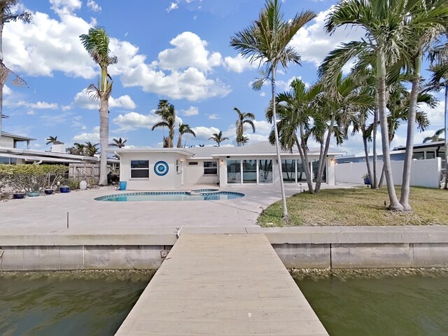 back of property with a water view, a fenced in pool, and a patio