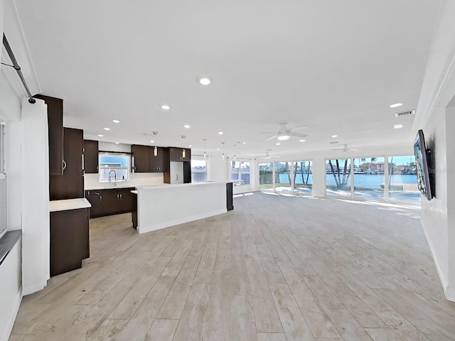 unfurnished living room with ceiling fan, light hardwood / wood-style flooring, and sink