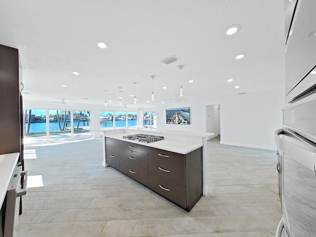 kitchen with plenty of natural light, a water view, decorative light fixtures, and a kitchen island