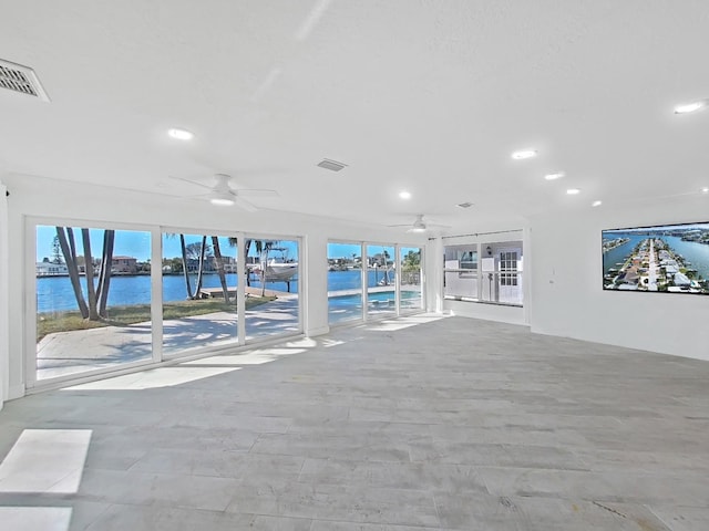 unfurnished living room with a water view and ceiling fan