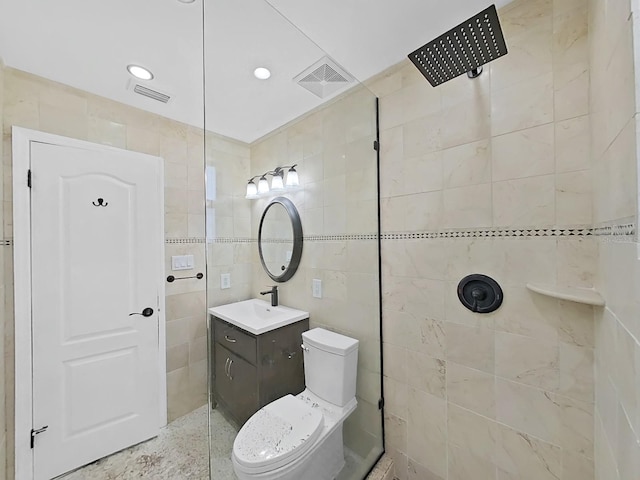 bathroom with vanity, toilet, tiled shower, and tile walls