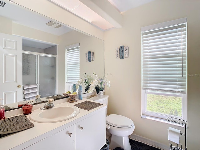 bathroom featuring vanity, a shower with shower door, and toilet