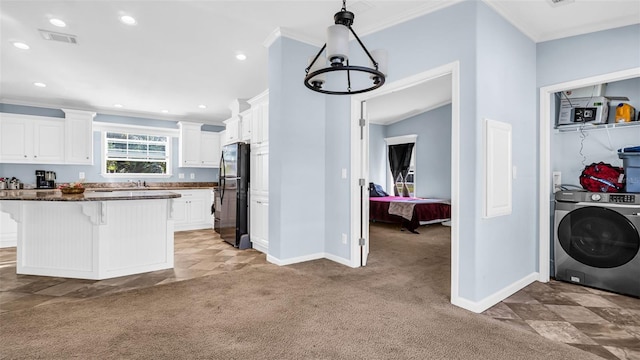 kitchen featuring black fridge, a breakfast bar area, light colored carpet, white cabinetry, and washer / dryer