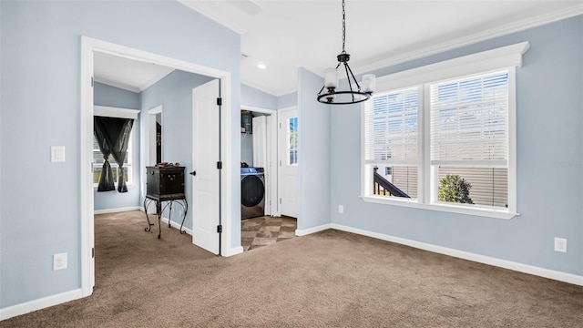 unfurnished dining area featuring carpet flooring, a notable chandelier, washer / dryer, and crown molding