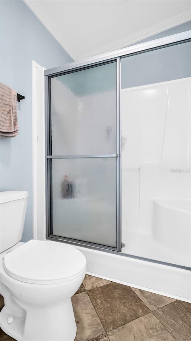 bathroom with tile patterned floors, crown molding, a shower with shower door, and toilet