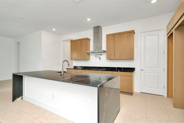 kitchen with sink, wall chimney range hood, stovetop, a kitchen island with sink, and light tile patterned floors