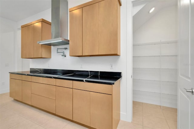 kitchen with wall chimney range hood, light brown cabinetry, light tile patterned floors, and black cooktop