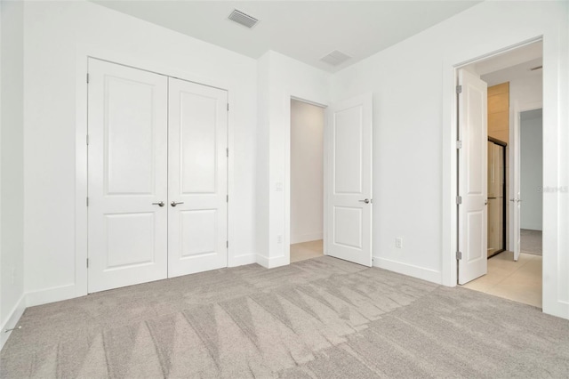 unfurnished bedroom with light carpet and a closet