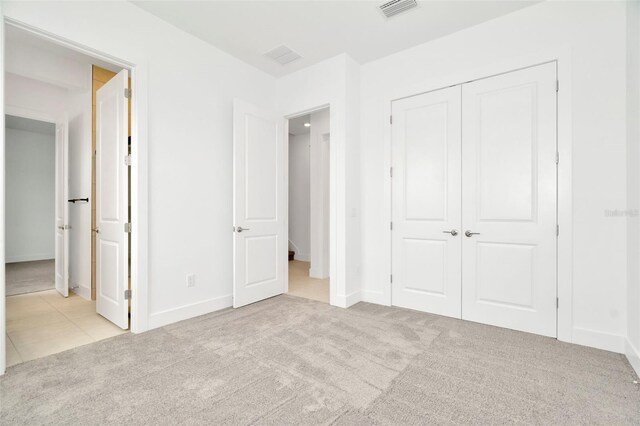 unfurnished bedroom with a closet and light colored carpet