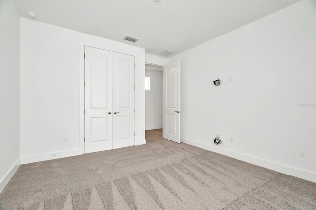 unfurnished bedroom featuring light carpet and a closet