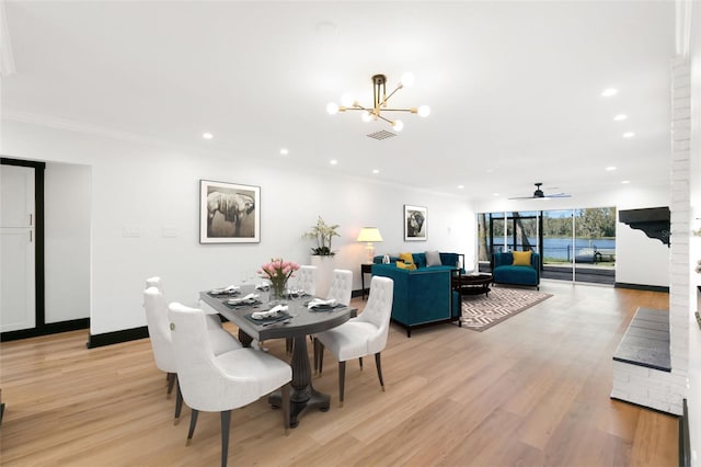 dining room featuring ceiling fan with notable chandelier, light wood-type flooring, and crown molding