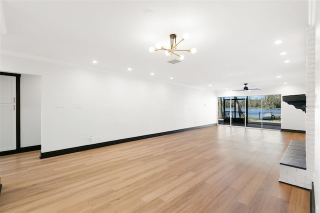 spare room featuring ceiling fan with notable chandelier, light wood-type flooring, and crown molding