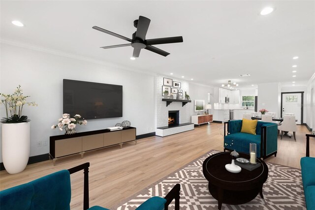 living room featuring a brick fireplace, ceiling fan, crown molding, and light hardwood / wood-style flooring