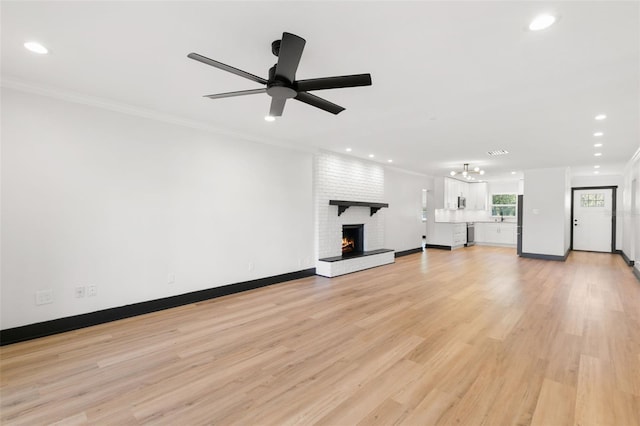 unfurnished living room featuring light hardwood / wood-style floors, a brick fireplace, ceiling fan, and ornamental molding