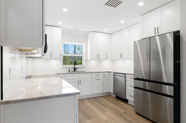 kitchen featuring sink, light stone countertops, light wood-type flooring, white cabinetry, and stainless steel appliances