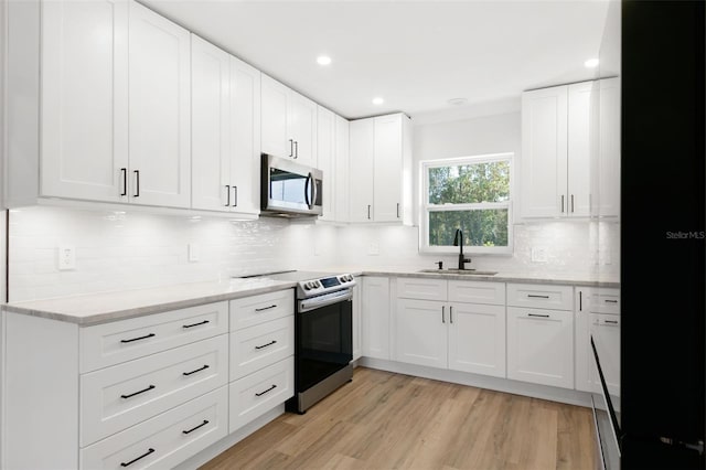 kitchen featuring white cabinets, appliances with stainless steel finishes, light hardwood / wood-style flooring, and sink