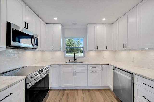 kitchen featuring stainless steel appliances, white cabinetry, light hardwood / wood-style floors, and sink