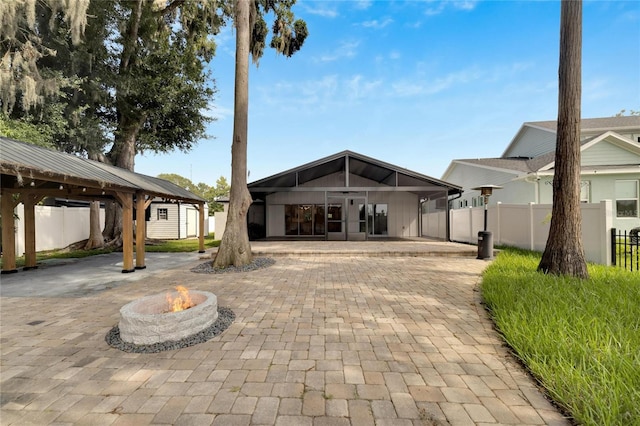 rear view of property with a gazebo, a patio, and a fire pit