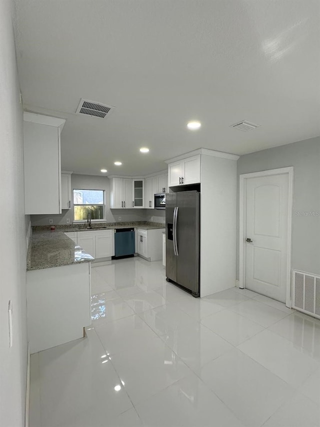 kitchen with sink, light tile patterned floors, appliances with stainless steel finishes, white cabinetry, and kitchen peninsula