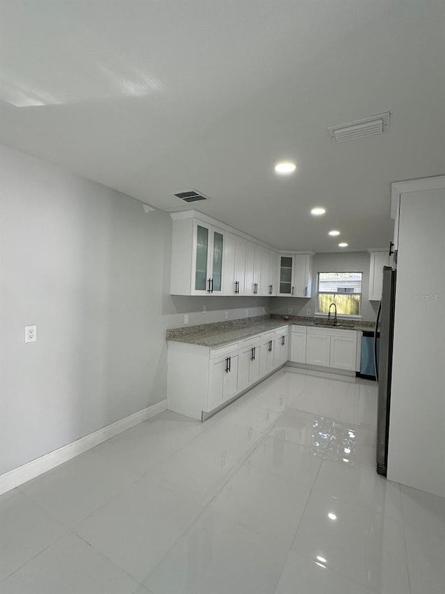 kitchen featuring white cabinets, stainless steel fridge, and sink