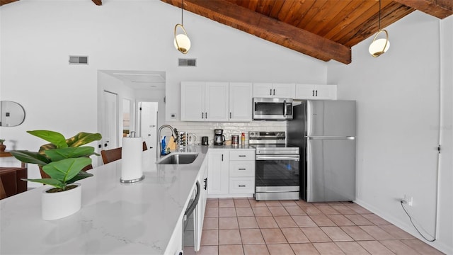 kitchen with sink, decorative light fixtures, beam ceiling, white cabinetry, and stainless steel appliances