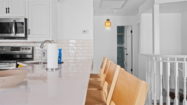 kitchen featuring white cabinets, decorative backsplash, stainless steel appliances, and sink