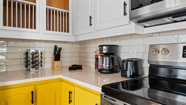 kitchen with backsplash, stainless steel appliances, and white cabinetry