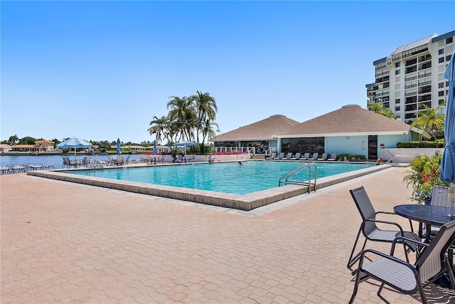 view of swimming pool featuring a patio and a water view