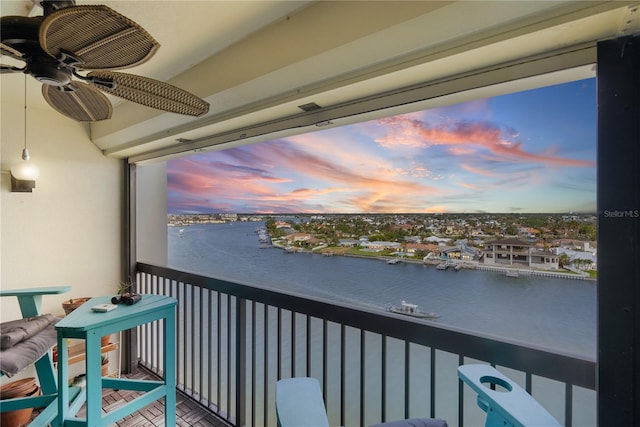 balcony at dusk with ceiling fan and a water view