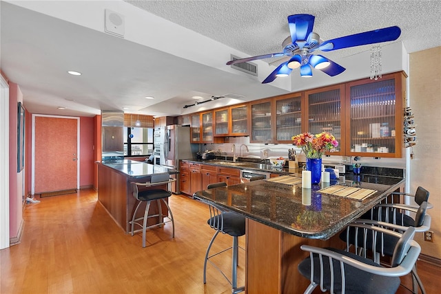 kitchen with stainless steel appliances, a center island, light hardwood / wood-style floors, and a breakfast bar area