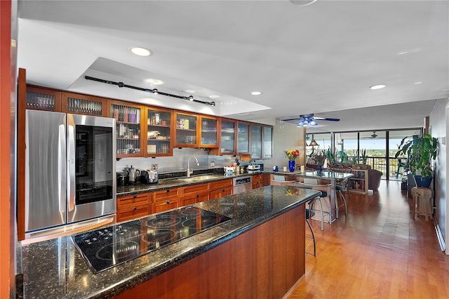 kitchen with sink, dark stone countertops, a breakfast bar area, light hardwood / wood-style floors, and stainless steel appliances