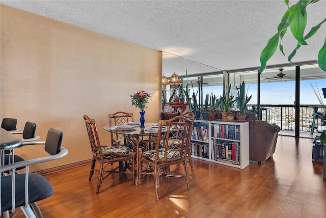 dining room with ceiling fan, wood-type flooring, floor to ceiling windows, and a textured ceiling