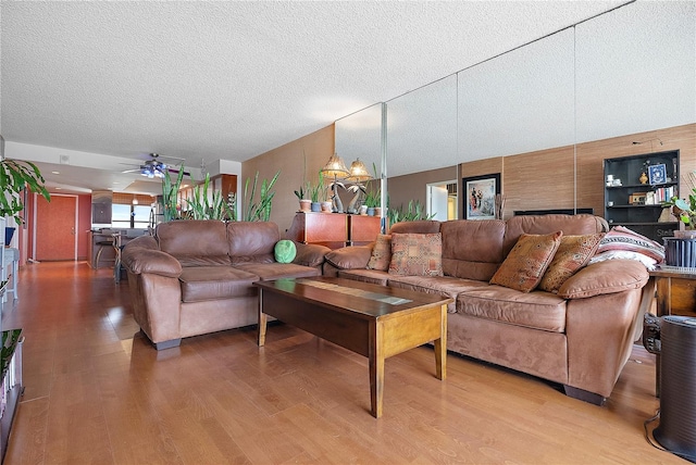 living room featuring wood-type flooring, ceiling fan, and a textured ceiling