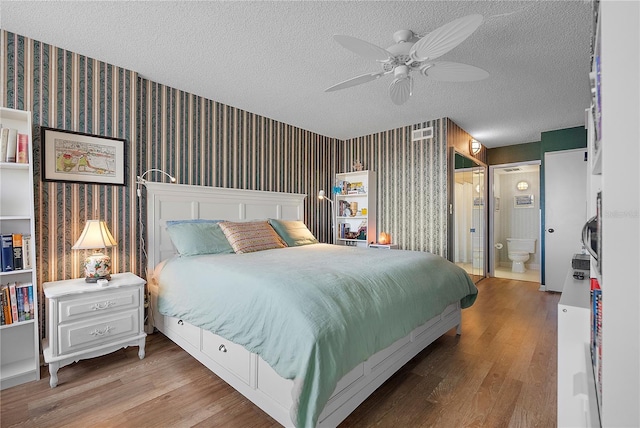 bedroom with connected bathroom, hardwood / wood-style flooring, a textured ceiling, and ceiling fan