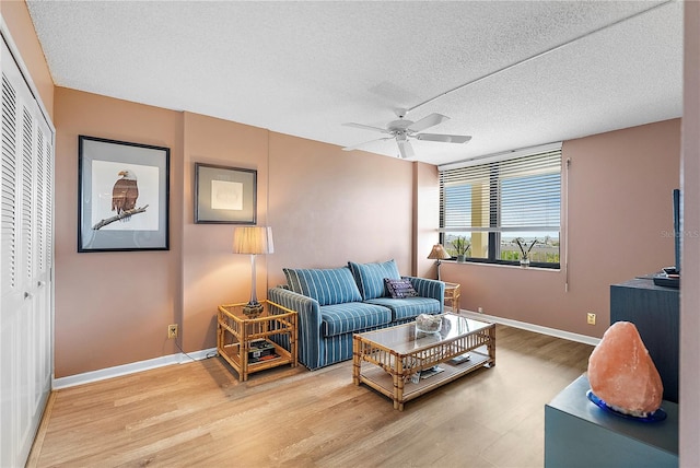 living room with ceiling fan, hardwood / wood-style flooring, and a textured ceiling