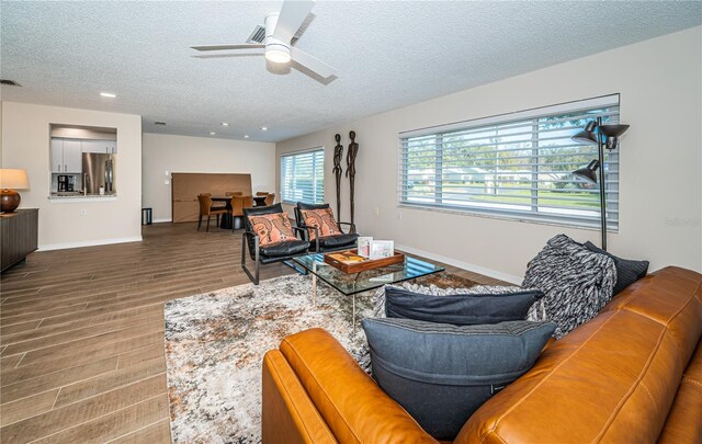 living room with a textured ceiling, hardwood / wood-style flooring, and ceiling fan