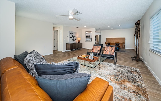 living room with ceiling fan, wood-type flooring, and a textured ceiling